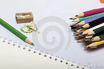 Stationery for school and teaching. Notepad and colored pencils for writing and drawing. Pencil sharpener with pencil shaving. Stock Photo