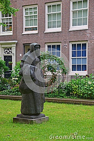 Statue of a Beguine in the beautiful courtyard of The Begijnhof at Amsterdam Stock Photo