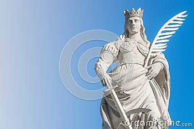 Statue of Catherin with writing bird feather, sword and cartwheel at ancient portal in Magdeburg, Germany, closeup, gradient blue Stock Photo