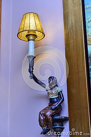 Statue holding a luminous lamp. Old antique Editorial Stock Photo