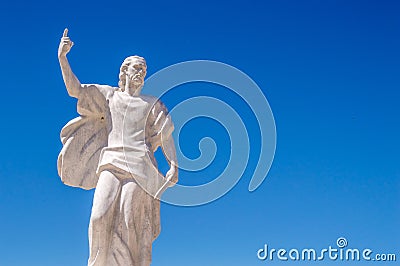 A statue of St Elijah the prophet holding a knife on a blue sky Stock Photo