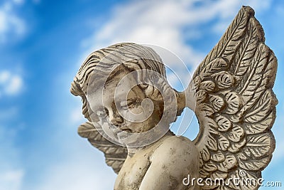 Statue of a grey stone angel against blue sky Stock Photo