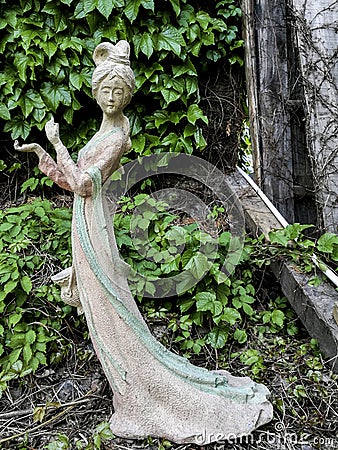 A statue of a white fairy found in an Abandoned Garden Editorial Stock Photo