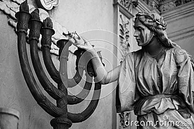 Statue of a woman lighting the middle of a seven candle chandelier Stock Photo