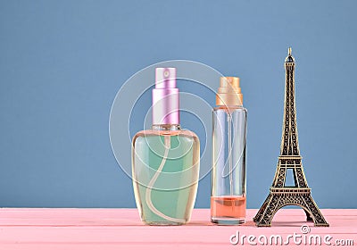 A statuette of the Eiffel Tower, bottles of perfume on a blue pastel background, minimalist trend, space for text, beauty Stock Photo