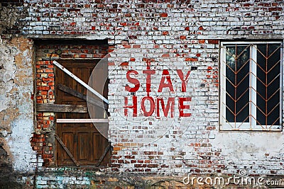 Stay home inscription on old brick wall .sealed door and barred window. Self-isolation at home from a coronovirus concept Stock Photo