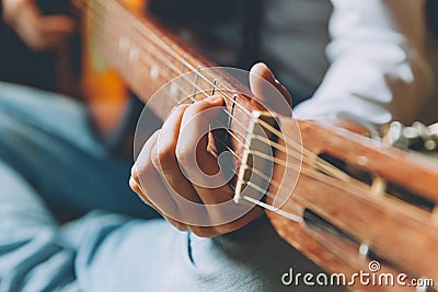 Stay Home Stay Safe. Young woman sitting at home and playing guitar, hands close up. Teen girl learning to play song and writing Stock Photo