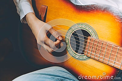 Stay Home Stay Safe. Young woman sitting at home and playing guitar, hands close up. Teen girl learning to play song and writing Stock Photo