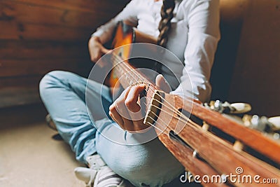 Stay Home Stay Safe. Young woman sitting at home and playing guitar, hands close up. Teen girl learning to play song and Stock Photo