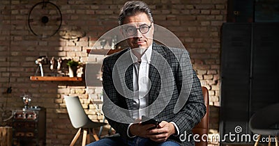 Smart looking older business man in home office using mobile phone for work. Stock Photo