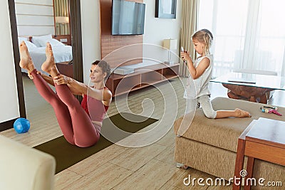 Stay At Home. Workout During Social Isolation. Mother Doing Exercise And Daughter Taking Photo On Smartphone. Stock Photo