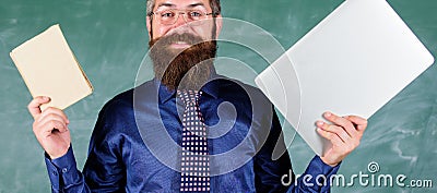 Stay modern with technology. Teacher bearded hipster holds book and laptop. Choose right teaching method. Teacher Stock Photo