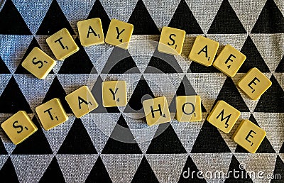 STAY SAFE STAY HOME - scrabble tiles against black and white textured background Editorial Stock Photo