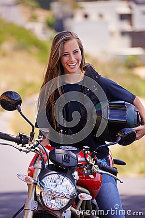 Staying true to the biker lifestyle. A beautiful young woman sitting on her motorcycle holding her helmet. Stock Photo