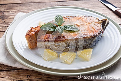 Steak baked fish salmon on a plate with lemon. Wooden table Stock Photo