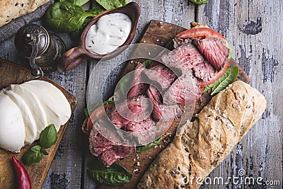 Steak sandwich, sliced roast beef, cheese,spinach leaves,tomato Stock Photo