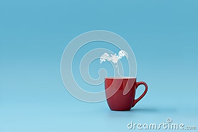 Steam in bat shape flying from coffee cup against blue background. Morning drink. Halloween celebration concept. Copy space Stock Photo