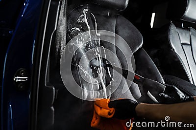 Steam cleaning of leather seat after foam and detergent washing. Worker in auto cleaning service clean car inside. Car Stock Photo