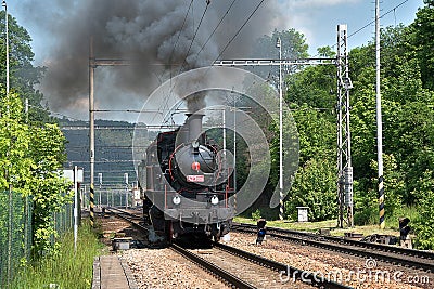 The steam locomotive departs from the station. Dense smoke rises from the chimney Editorial Stock Photo