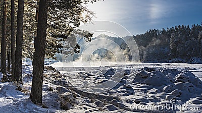 Steam rises over a thawed section of a frozen river. Stock Photo