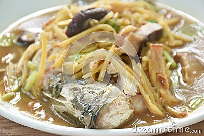 steamed bass fish dressing soybean gravy sauce topping slice ginger and mushroom on plate Stock Photo
