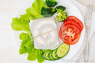 Steamed cod fish. Paleo, keto, fodmap healthy diet with vegetables on white plate on white table, top view. Stock Photo