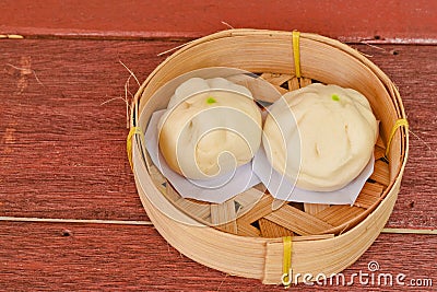 Steamed pork buns or Chinese bun in bamboo basket put on a texture wooden Stock Photo