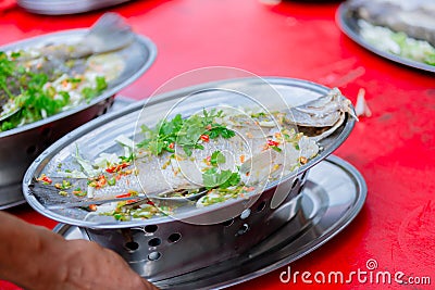 Steamed sea bass fish with lemon, Thai famous local food served on fish shape plate. Stock Photo