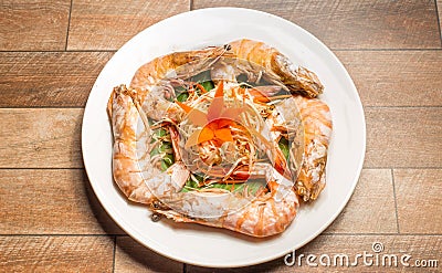 Steamed seafood or Steamed shrimp with herbs and vegetable in white dish on wood table. Stock Photo