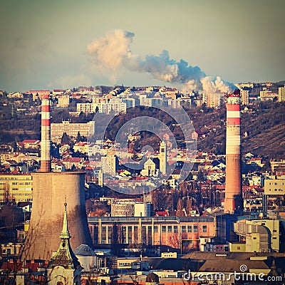 Steaming chimneys with houses in the city. Concept for environment and industry. Background with city landscape at sunset. Brno - Editorial Stock Photo