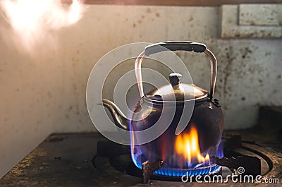 Steaming water in Traditional metal kettle on fire on gas stove Stock Photo