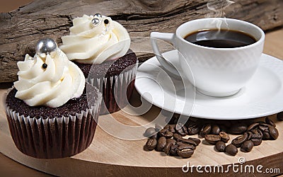 Steaming white coffee cup, homemade cupcake and coffee beans on brown wooden background, homemade cake Stock Photo