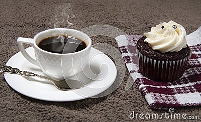 Steaming white coffee cup and homemade cupcake on brown fabric background, homemade cake Stock Photo