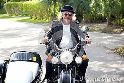 Steampunk biker driving sidecar motorcycle towards viewer Stock Photo