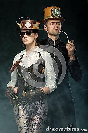 Steampunk couple. Man with a pipe and a girl with glasses and h Stock Photo