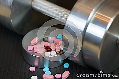 Steel dumbbell and colorful vitamins pills on the gym mat Stock Photo