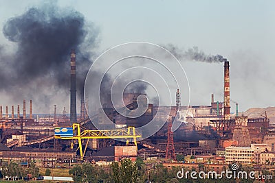 Steel factory with smog at sunset. Pipes with black smoke Stock Photo