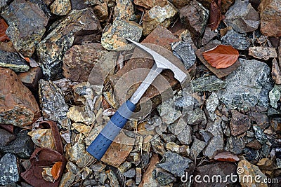 Steel geologist rock pick over brown and grey rocks in chromite mining area in Troodos mountains, Cyprus Stock Photo