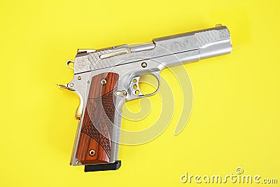 Steel gun or pistol inlaid with wood and gold isolated on a yellow background. weapon concept. protection and violence. copy space Stock Photo