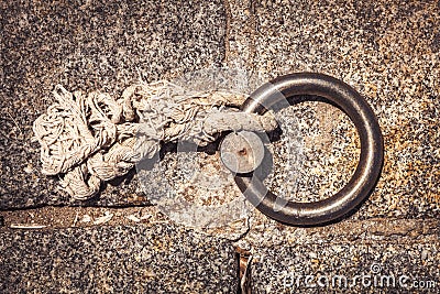 Steel ring and mooring lines in a seaport. Light colored hemp rope on the concrete ground Stock Photo