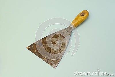 Old steel trowel scraper or spatula wooden handle isolated on blue background Stock Photo
