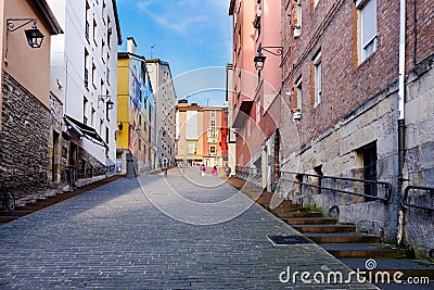 Steep cobblestone street with facades of old houses with lots of color on the sides Stock Photo