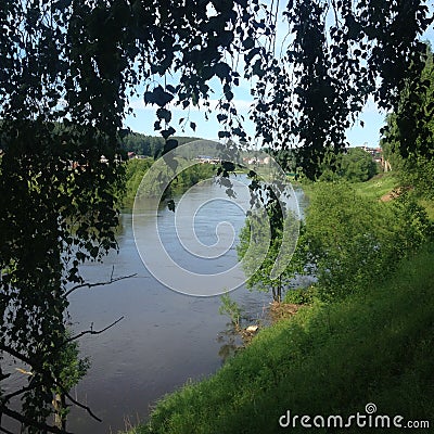 Steep green banks by a calm, deep river. Stock Photo