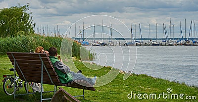 Couple relaxing on a bench eating ice cream and enjoying the view of the lake Editorial Stock Photo