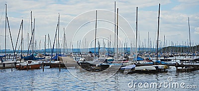 Many small sailing boats with masts without rigging anchor at a landing stage in the harbour of the big lake Editorial Stock Photo