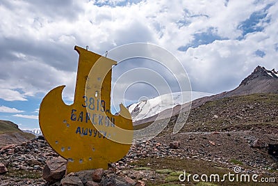 Stella on the road to Kumtor gold mine with inscription in Kyrgyz language - Stock Photo