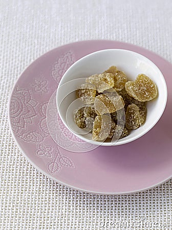 Stem ginger in white bowl pink plate. Conceptual image Stock Photo