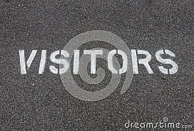 Stenciled `VISITORS` Spray Painted on Pavement of Parking Lot Stock Photo