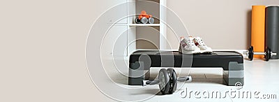 Step platform, sneakers and abdominal wheel indoors, space for text. Banner design Stock Photo