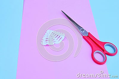step-by-step process of cutting out snowflakes from white paper for new year and Christmas on the background of bed tones Stock Photo